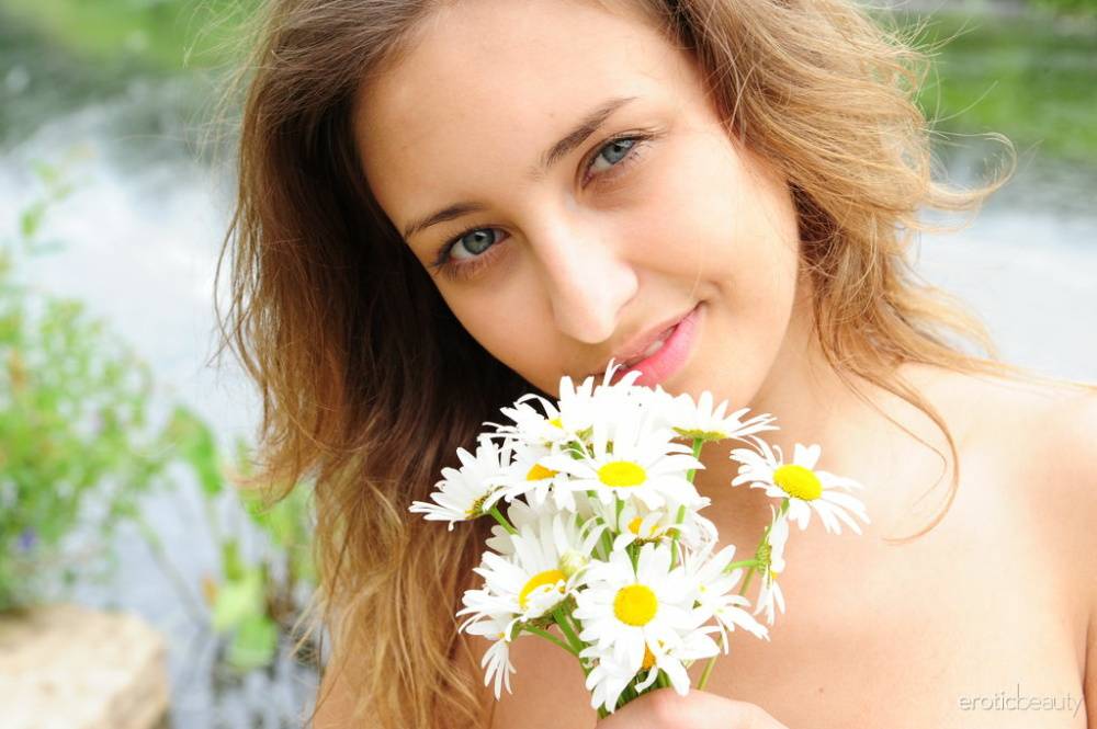 Teen model Dana B holds fresh picked flowers while naked by a river - #7
