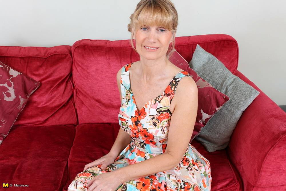 Mature woman takes off her dress and pretties to on a red sofa - #5