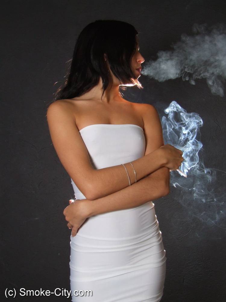 Young brunette smokes a cigarette while wrapped in tight white dress and heels - #1