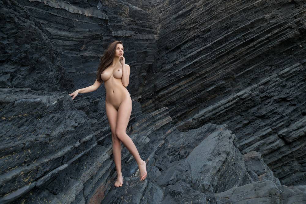 Totally naked girl Alisa I models up against a sea cliff during solo action - #2