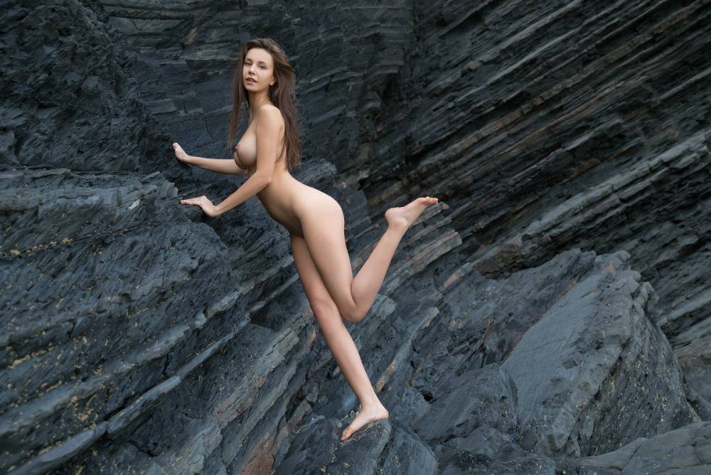 Totally naked girl Alisa I models up against a sea cliff during solo action - #11