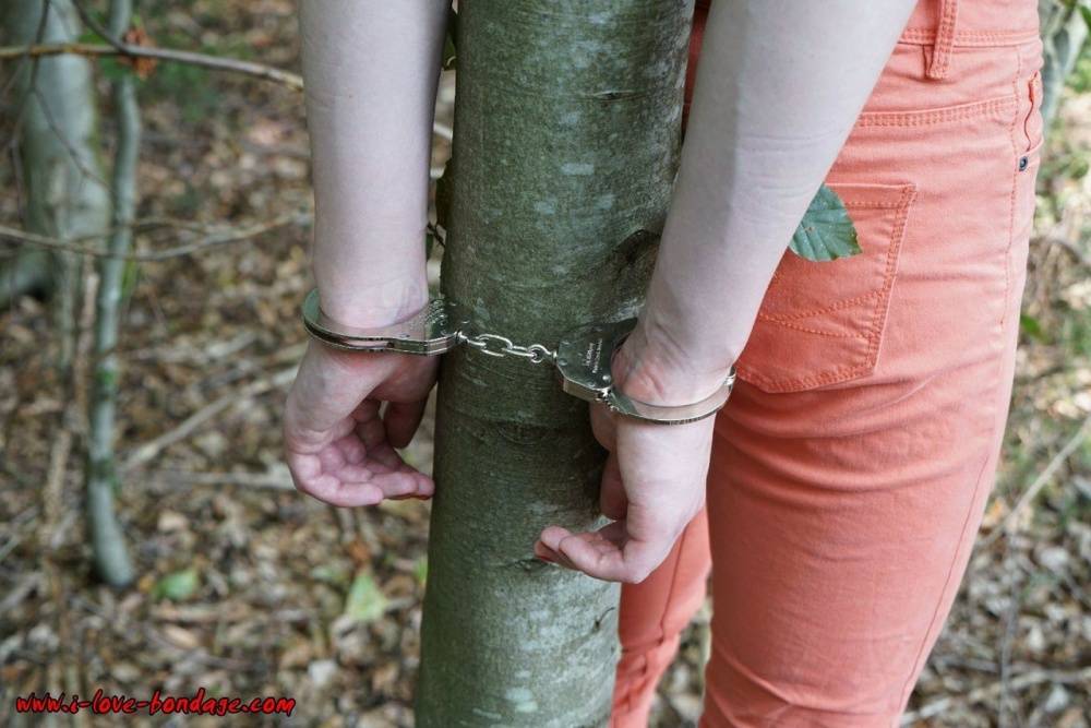 Clothed girl in canvas sneakers finds herself handcuffed to a tree in woods - #1