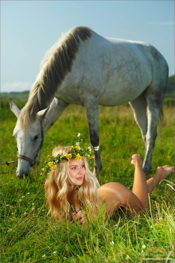 Adorable blond wear a crown of wildflowers while modeling nude against a horse - #12