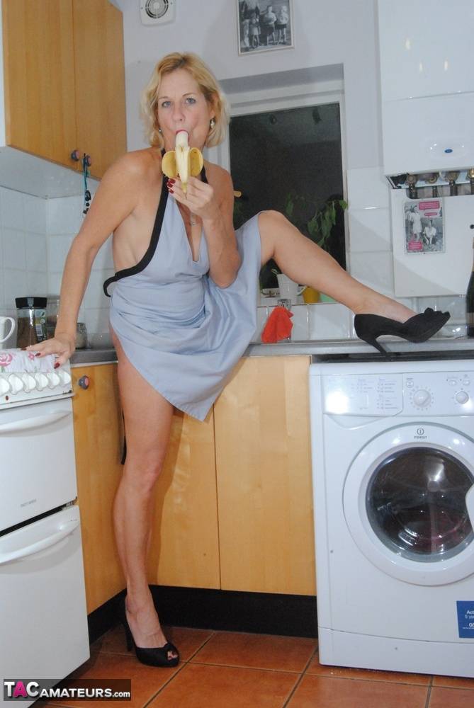 Mature MILF with blonde hair wears only an apron while devouring a banana - #15