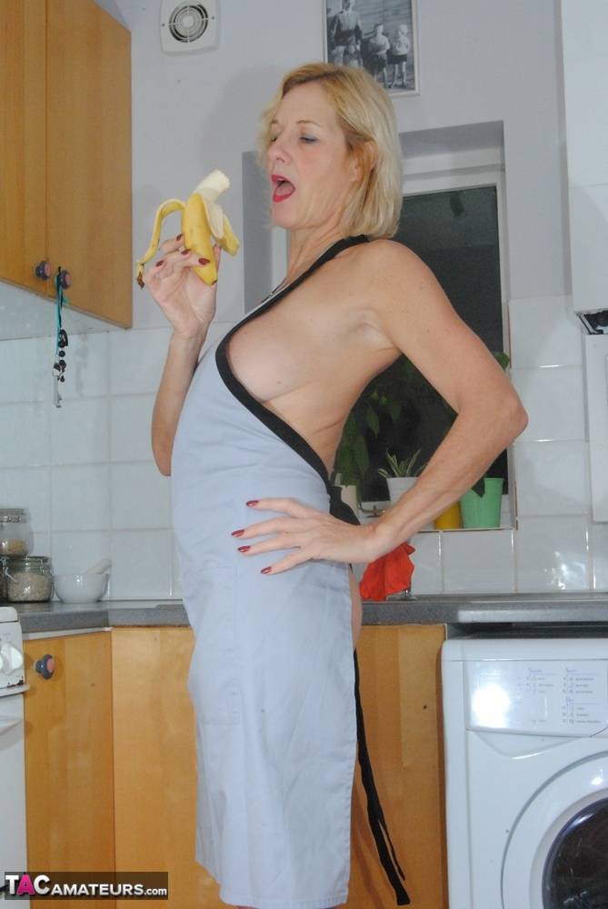 Mature MILF with blonde hair wears only an apron while devouring a banana - #1
