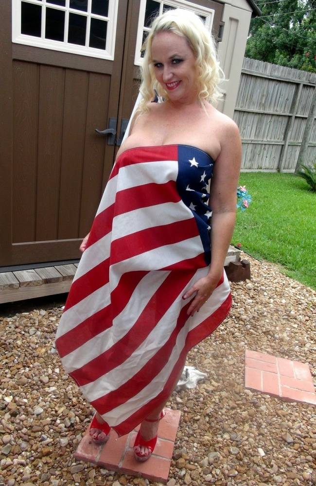 Blond amateur Dee Siren holds a USA flag while showing her big tits in a thong - #1