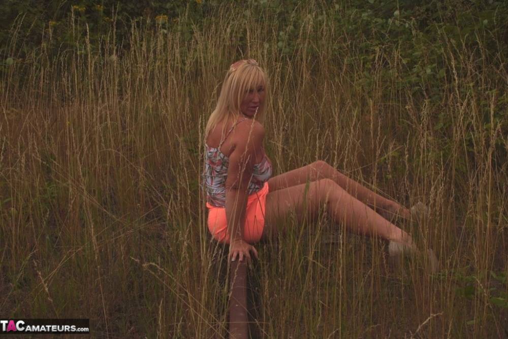 Blonde amateur Melody reveals her big natural tits in a field behind her place - #1