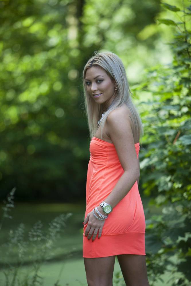 Natural blonde Natalia Forrest displays her MK watch up against a hedge - #1