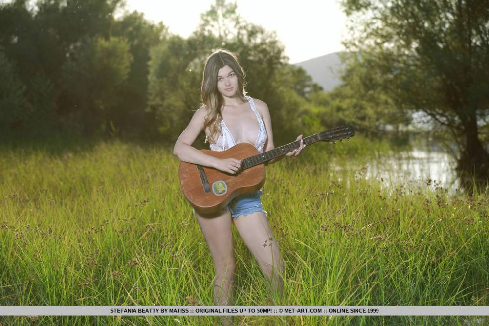 Nice teen Stefania Beatty gets totally naked in a field while playing guitar - #6