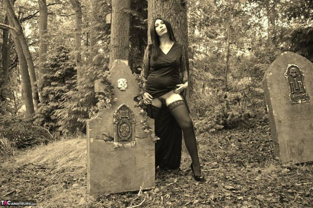 Goth girl Barby Slut bares her big tits and twat atop a casket in the woods - #1
