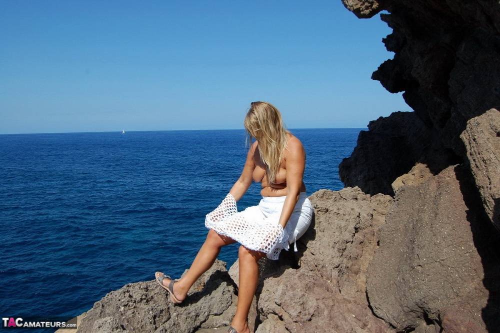 Blonde amateur Sweet Susi exposes her tits and ass on a rocks by the sea - #13