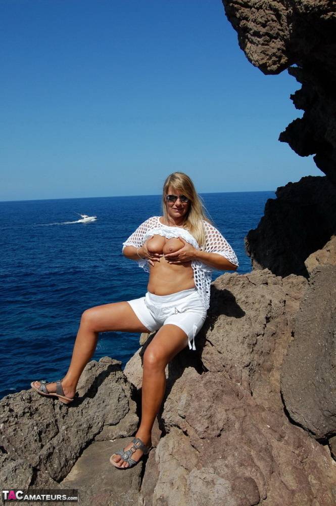Blonde amateur Sweet Susi exposes her tits and ass on a rocks by the sea - #11