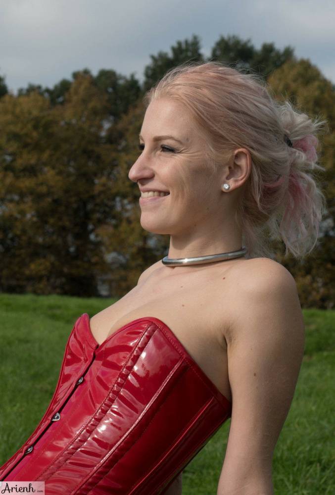 Collared girl Arienh Autumn models a red leather corset while in a field - #15