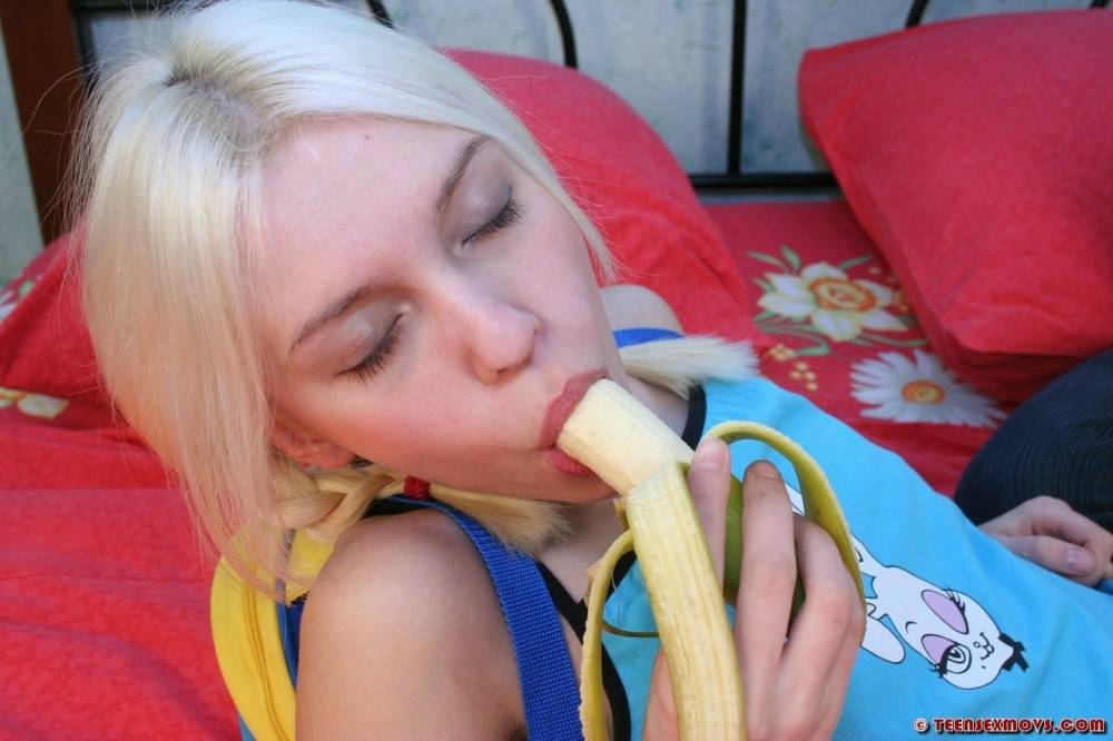 Young looking blonde eats a banana during close-up fucking on a bed - #4