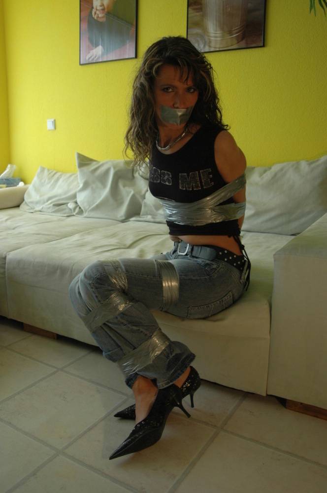 Clothed female is silenced and restrained with duct tape on a sofa - #3