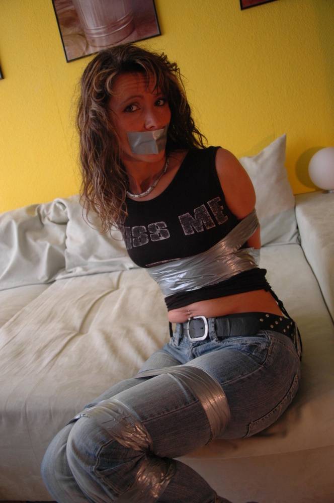 Clothed female is silenced and restrained with duct tape on a sofa - #11