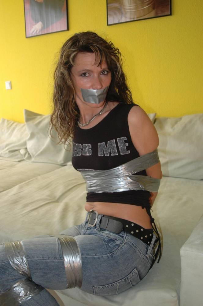 Clothed female is silenced and restrained with duct tape on a sofa - #1