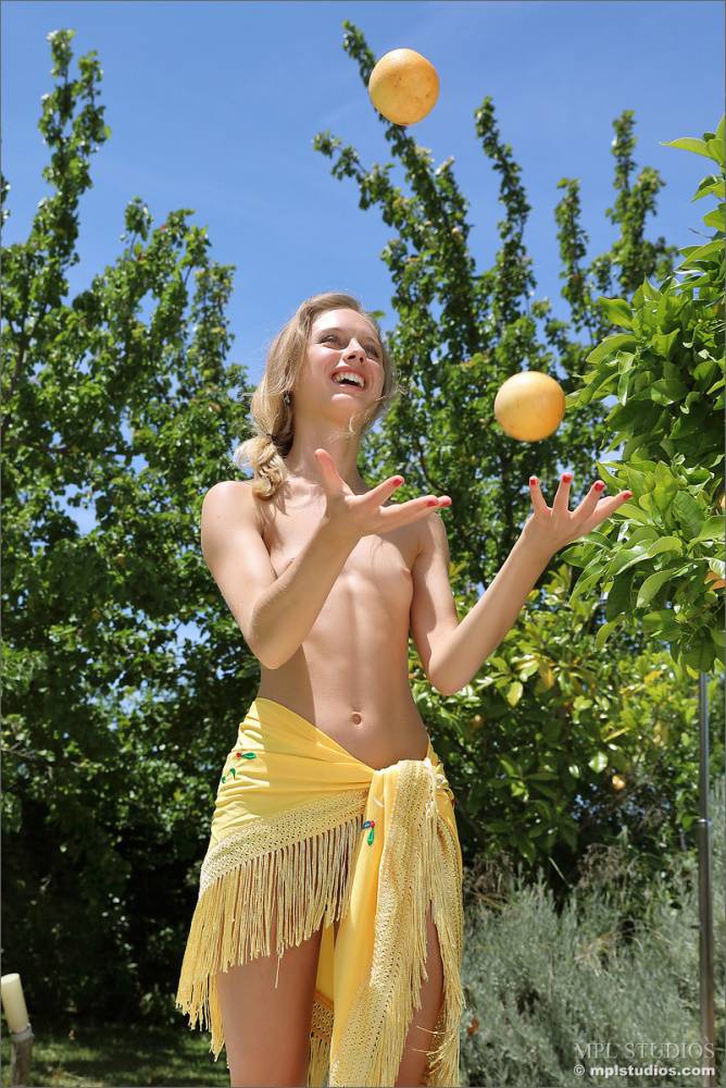 Blonde model juggles oranges before getting totally naked on a patio - #2