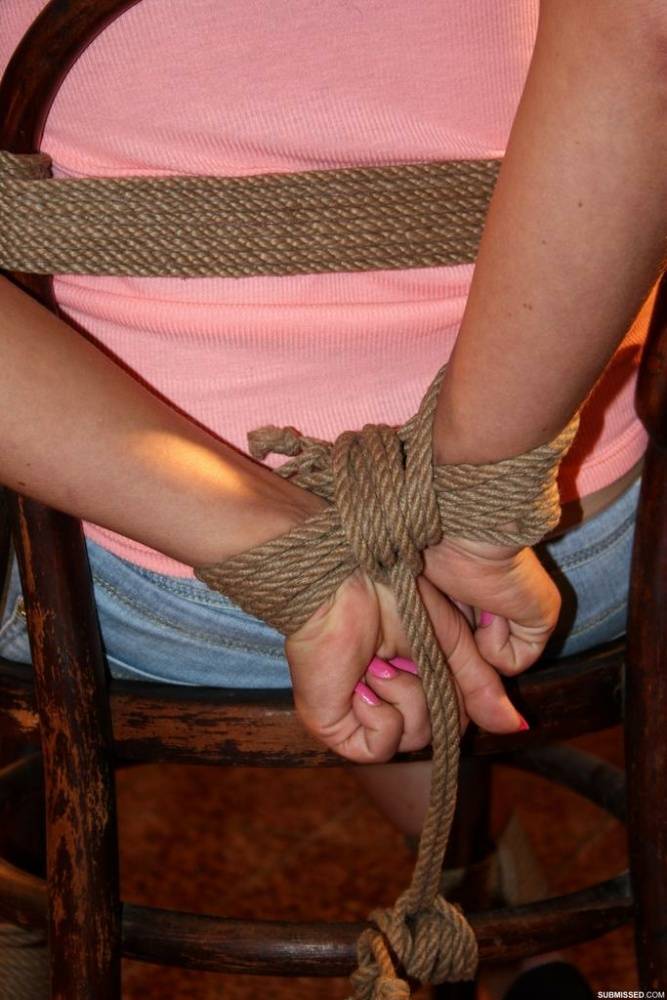 Blonde female in denim shorts is gagged and tied to a chair in an empty room - #9