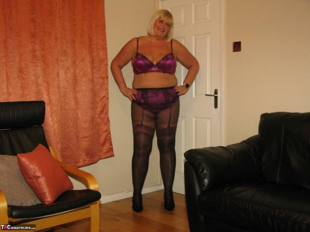Older blonde BBW Chrissy Uk models lingerie & pantyhose on a leather loveseat - #11