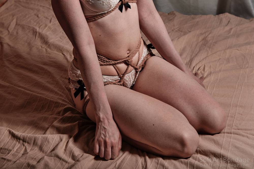 Caucasian female in bra and panty ensemble models on bed while tied with rope - #3