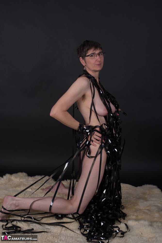 Naked older lady covers herself in tape during solo action on a rug in glasses - #9