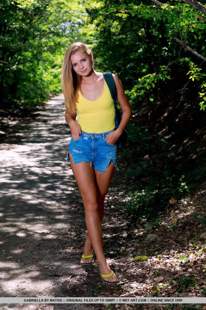Petite teen Gabriella crosses bare legs before posing nude on a path in woods - #13
