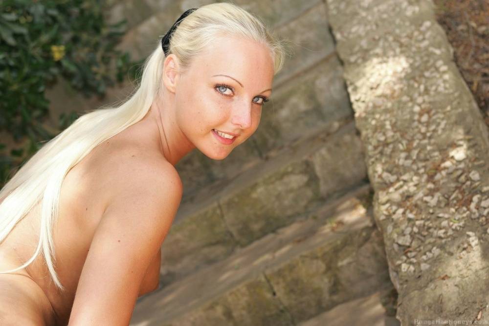 Blonde girl takes off her pink bikini in the shade on stone steps - #11