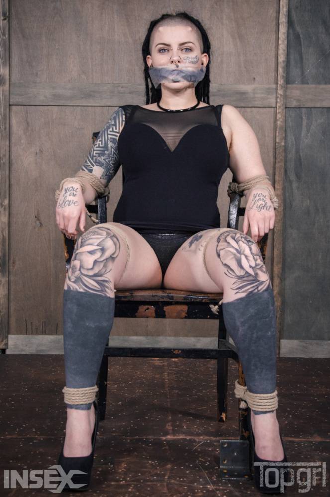 Pierced and tatted girl is worked over by a woman while restrained in bondage - #1