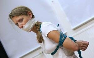 Clothed woman sports a pigtail while being gagged and tied up with rope - #main