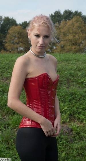 Collared girl Arienh Autumn models a red leather corset while in a field - #main