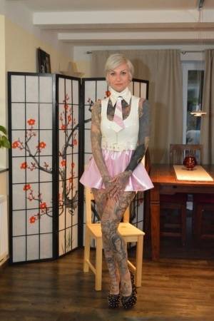 Tattooed platinum blonde Miss Francine models a raincoat over a latex dress - #main