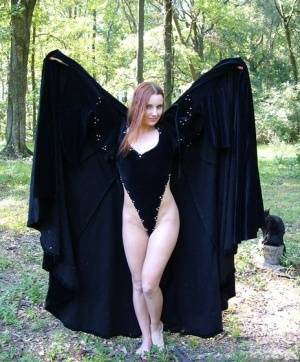 Redhead amateur Amber Lily models nude in a forest draped in a black cape on clubgf.com