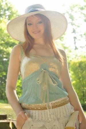 Natural redhead Charlie Edwards removes a sunhat while getting naked in a yard on clubgf.com