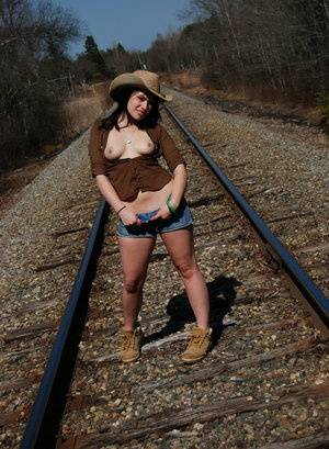 Young amateur Emily Love exposes herself on railway tracks in a hat and boots on clubgf.com