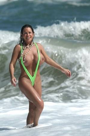 Amply endowed female Alicia Dimarco struts in a v-bikini amid foamy surf on clubgf.com